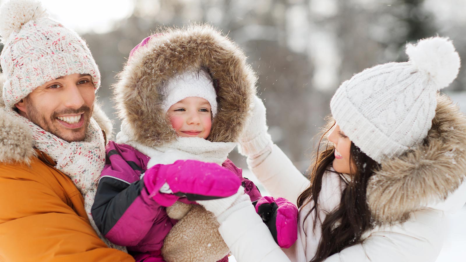 Due genitori giocano con la figlia sulla neve