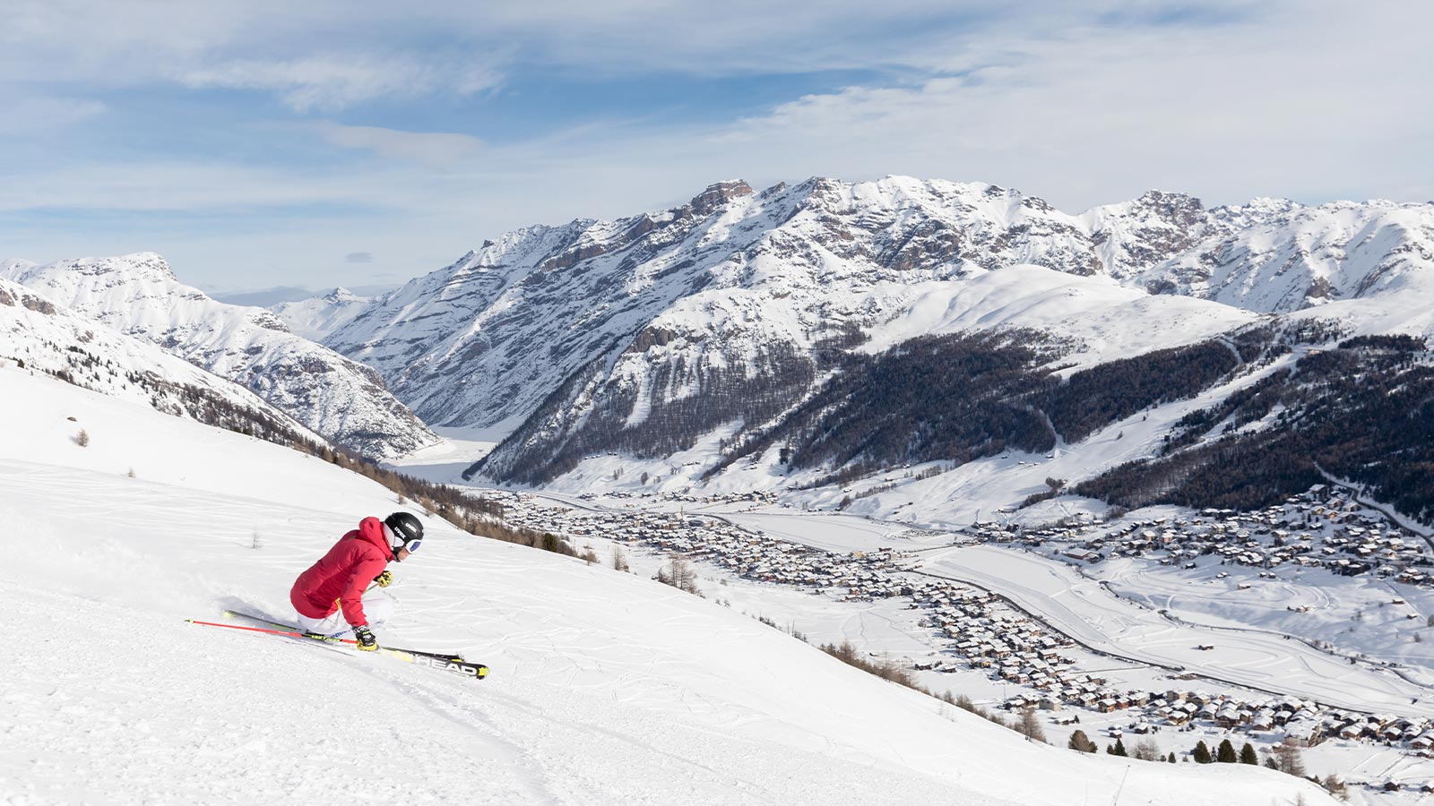 Uno sciatore si diverte sulle piste da sci di Livigno, con vista panoramica sulla cittadina